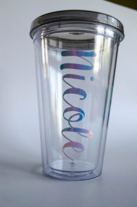 an empty plastic reusable tumbler with the name Nicole monogrammed on the outside in holographic vinyl