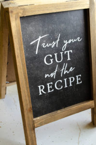 wooden sign with chalkboard center that reads trust your gut not the recipe