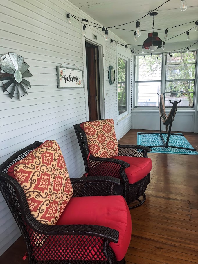front porch with hanging lights and red rocking chairs with hammock in the background
